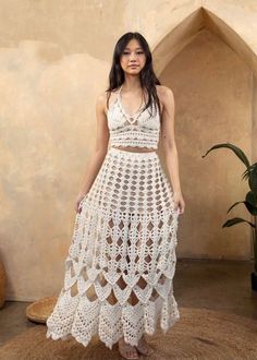 a woman in a white crochet dress standing on a rug