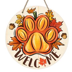 a wooden sign that says welcome with an image of a dog's paw and autumn leaves