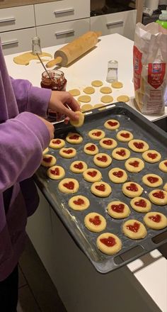 a woman is making cookies with jam on them