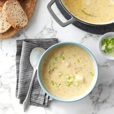 two bowls filled with soup next to some bread on top of a white marble counter