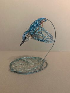 a wire sculpture with a bird sitting on top of it's head in the air