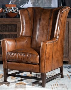 a brown leather chair sitting on top of a rug