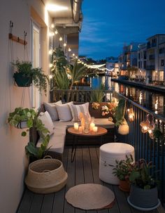 the balcony is decorated with potted plants and lit candles on the table next to the couch