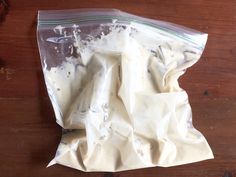 a plastic bag filled with white frosting on top of a wooden table