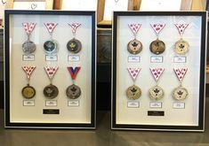 two framed medals on display in front of windows