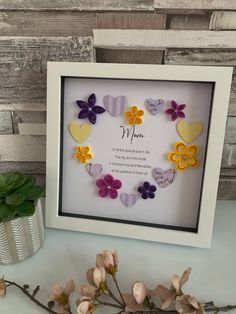 a white frame with flowers and hearts on it next to a vase filled with flowers