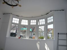 an empty room with three windows and a ladder in front of the window that has been painted white