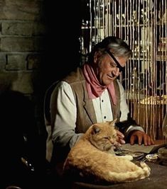 an old man sitting at a table with a cat