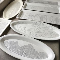 four white plates sitting on top of a table next to each other with designs painted on them