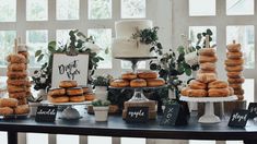 a table topped with lots of donuts covered in frosting next to cakes and cupcakes