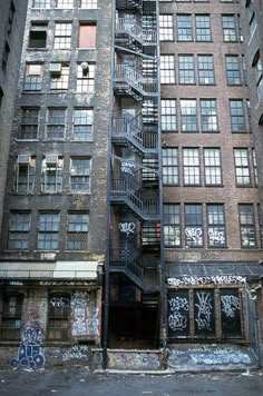 an old building with graffiti all over it's walls and staircase leading up to the second floor