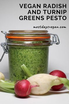 a jar filled with green pest sitting next to radishes and celery