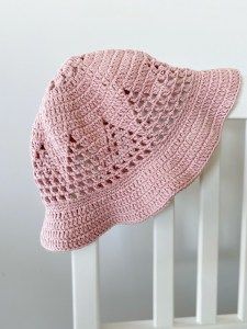 a pink crocheted hat sitting on top of a white chair