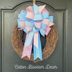 a wreath with pink, blue and white bows hanging on the front door