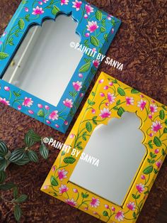 two boxes with flowers painted on them and one has a mirror in the top half