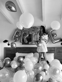 a woman standing on top of a bed in front of balloons and heliums that spell out the word love