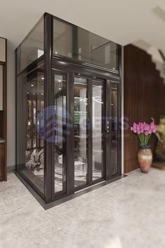 an empty room with glass doors and flowers in vases on the floor next to it