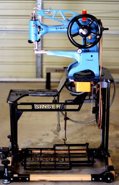 an old sewing machine sitting on top of a cart in a garage with the word singer written on it