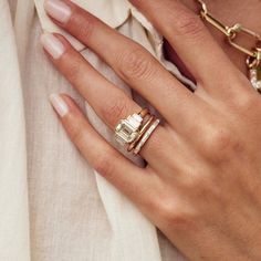 a close up of a person's hand with two rings on their fingers and an engagement ring