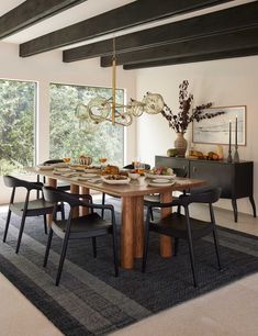 a dining room table with chairs and a chandelier hanging from it's ceiling