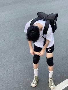 a man with knee pads and a backpack on his back is standing in the street