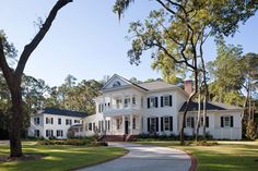 a large white house sitting on top of a lush green field