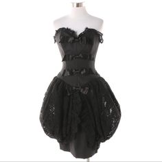 A Vintage 1980s Victor Costa Black Textured Fabric And Black Lace Corset Dress. This Stunner Is Designed With A Lace Accented Sweetheart Neckline And Back, A Row Of Four Sateen Bows To The Front, And A Fitted Skirt Featuring Ruffle Edged Lace Bustle Accents To The Sides. There Is A Hidden Zipper To The Back And A Brand Label Sewn To The Black Lining. Retains Original Retail Tag. - 30" Bust, 24" Waist, 32" Hip, 29" Length Including Lace. Gothic Black Vintage Dress For Party, Black Fitted Corset Dress With Ruffles, Black Overbust Corset Dress For Formal Occasions, Black Corset Dress With Lace Trim For Formal Occasions, Black Formal Corset Dress With Lace Trim, Black Gothic Corset Dress For Cocktail, Fitted Vintage Black Dress With Lace Trim, Fitted Black Vintage Dress With Lace Trim, Black Fitted Sleeveless Vintage Dress