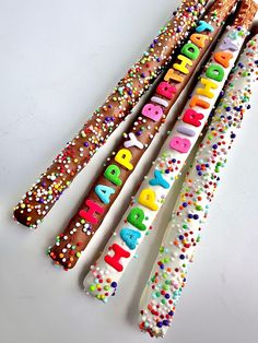 three birthday candles with sprinkles and the words happy on them are lined up