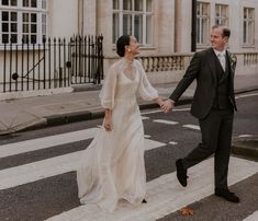 a bride and groom crossing the street holding hands