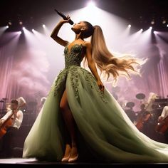 a woman in a green dress standing on stage with her hair blowing in the wind