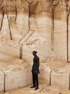 a man standing in front of large rock formations