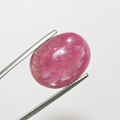 a pink stone sitting on top of two metal pins