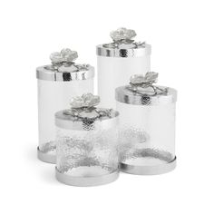 three clear glass containers with silver flowers on them