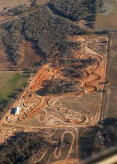 an aerial view of a large dirt track in the middle of a field with lots of trees