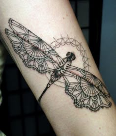 a black and white photo of a dragonfly tattoo on the left arm with lacework