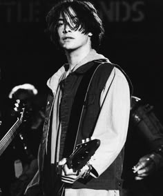 black and white photograph of a young man holding an electric guitar in front of him