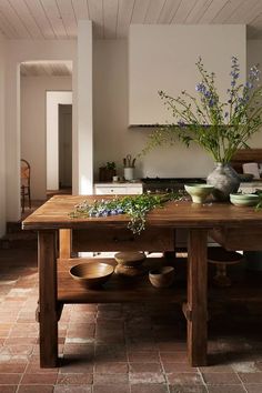 a wooden table topped with bowls and vases filled with flowers on top of it