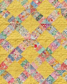 a yellow quilt with many different colored squares on the top and bottom, all over it