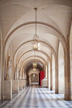 the hallway is lined with statues and chandeliers