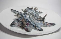 a white plate topped with dried fish on top of a table