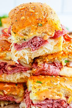 several sandwiches stacked on top of each other with meat, cheese and vegetables in the middle