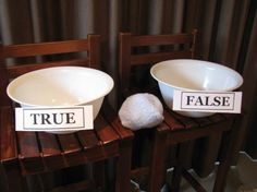 two white bowls sitting on top of wooden chairs with signs reading true and false in front of them