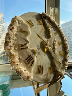 a clock made out of shell with gold roman numerals