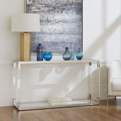 three vases are sitting on a table in front of a wall with a painting