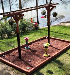 an outdoor garden with flowers and plants in the ground next to a body of water