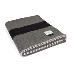 a gray and black blanket folded up on top of a white surface with a tag attached to it