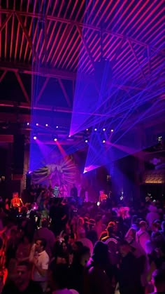 a large group of people in a room with purple lights on the ceiling and floor