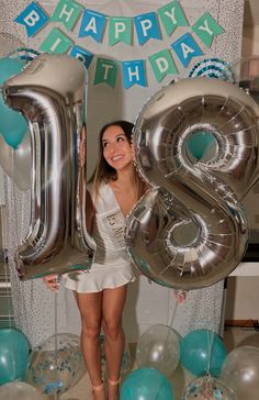 a young woman holding up the number twenty eight in front of balloons and streamers