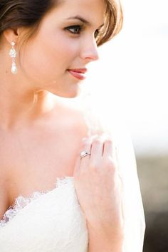 a woman wearing a wedding dress and diamond earrings