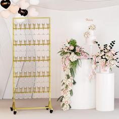 two tall white vases with flowers on them next to a gold and white cake stand